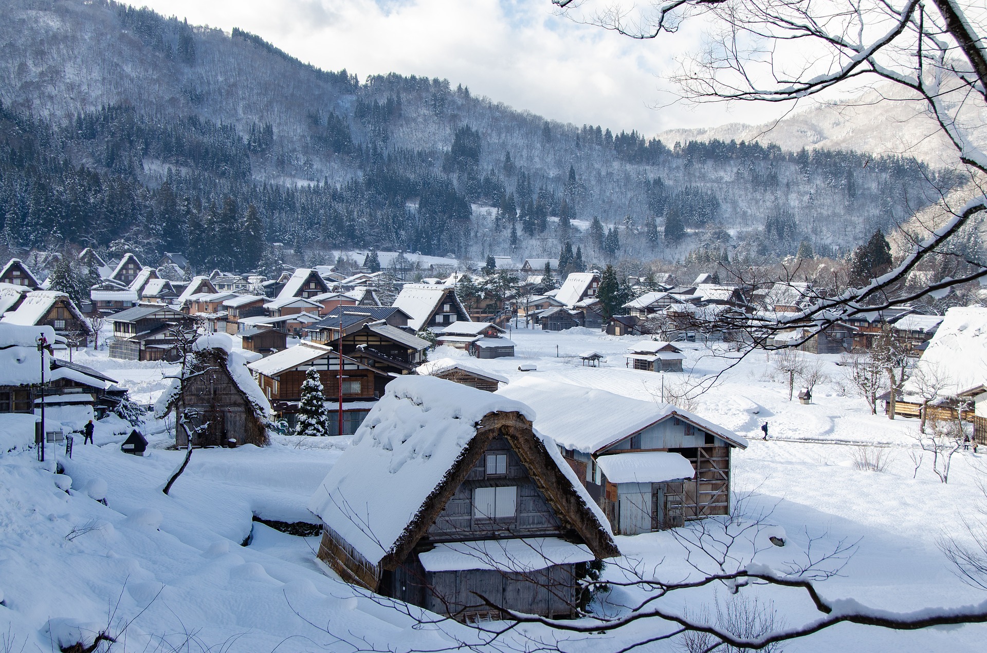 Foto de un pueblo japonés en la montaña, con todo el paisaje nevado y los tejados de las casas cubiertos de nieve.