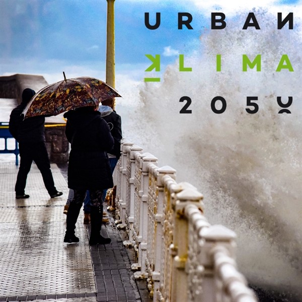 Imagen en la que aparecen varias personas con paraguas junto a la barandilla de un paseo marítimo golpeado por las olas. Encima de las olas se lee "URBAN KLIMA 2050".
